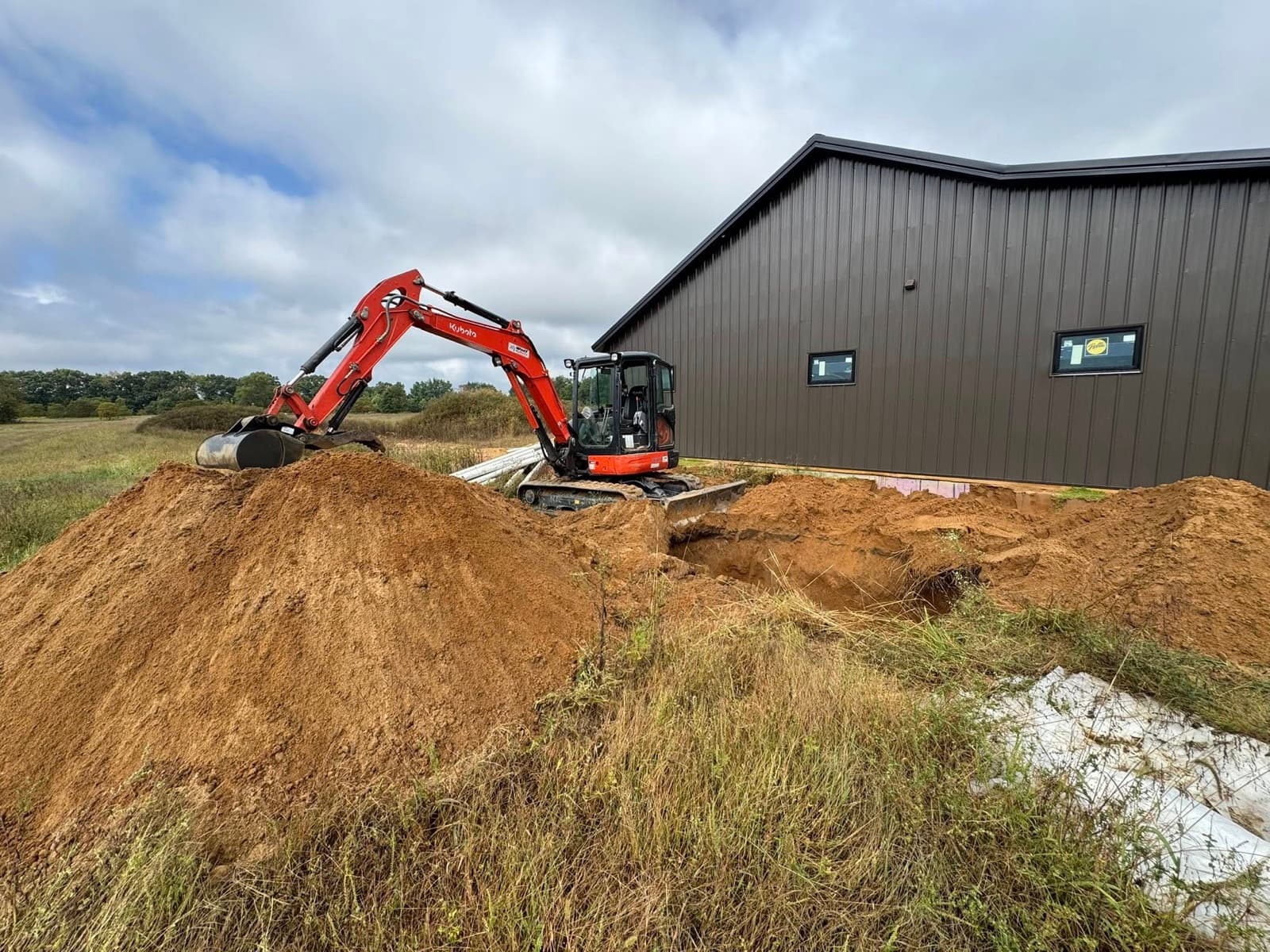 Kubota mini-excavator digging at a new install site