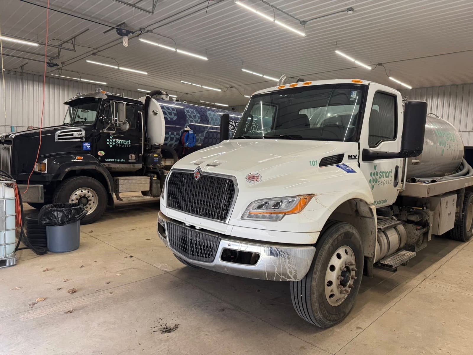 Two Smart Septic pumping trucks parked in the heated shop